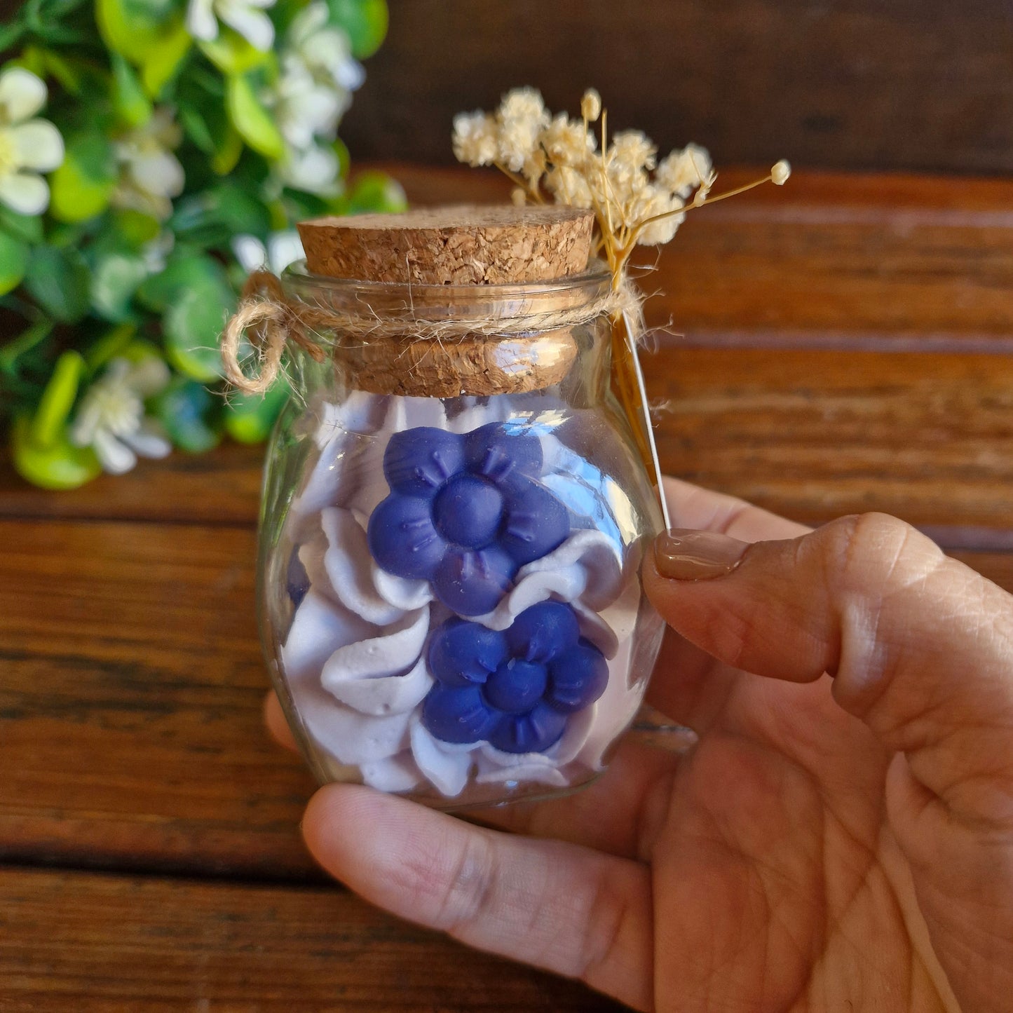 Vela decorativa aromática con flores en recipiente de vidrio con tapa de corcho